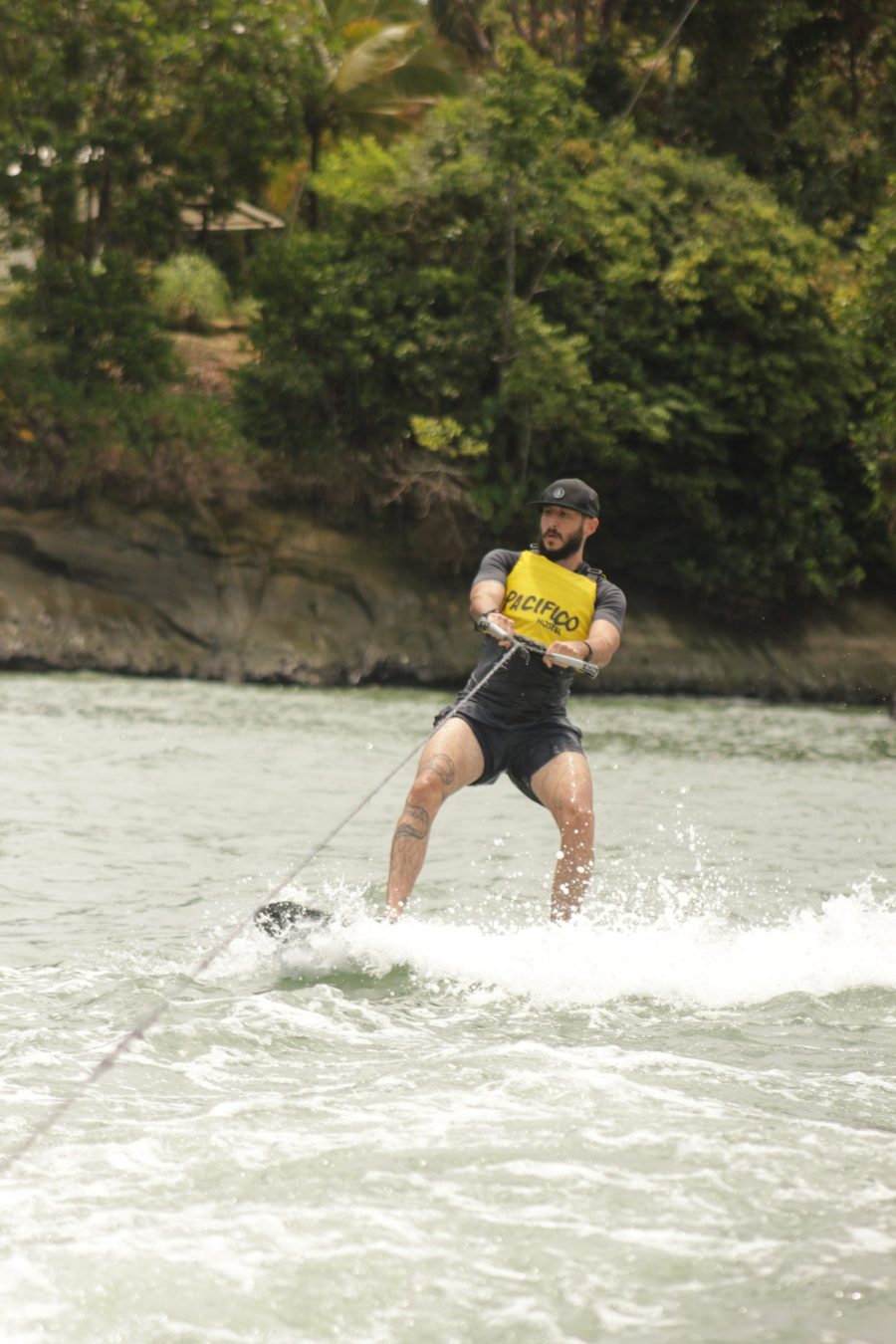 Persona practicando wakeboard en la bahía del Parque Nacional con chaleco salvavidas Pacífico