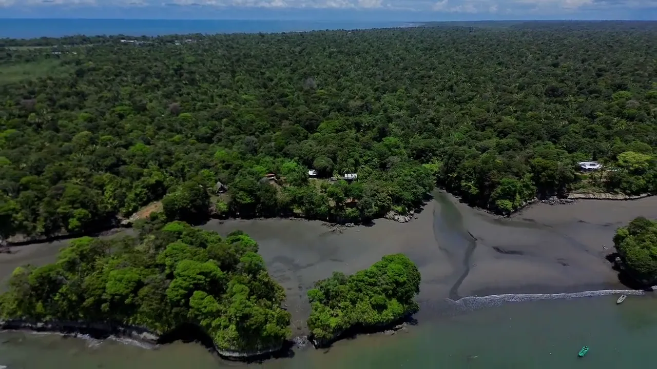 Playa Escondida con marea baja: arena oscura, islotes y selva