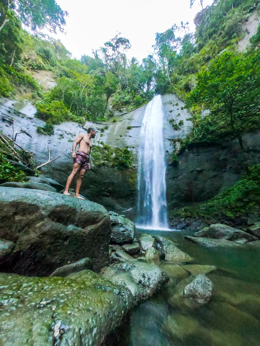 Viajero junto a una cascada entre rocas y selva