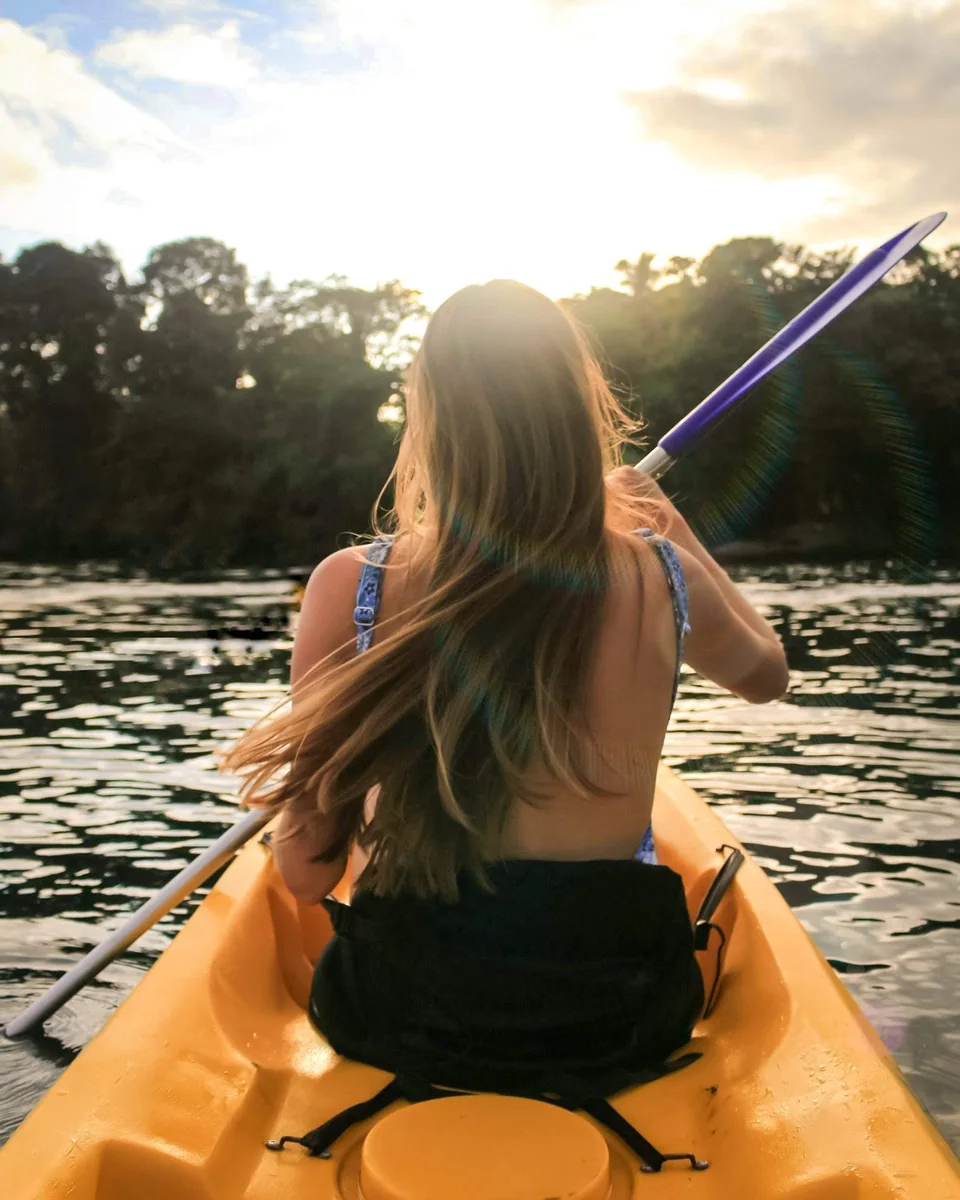 Viajero de espaldas remando en un kayak naranja